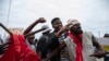 Manifestantes seguram uma cruz com a bandeira do partido Frente de Libertação de Moçambique (FRELIMO) enquanto protestam no bairro de Hulene, em Maputo, a 31 de outubro de 2024, durante o primeiro dia da greve nacional convocada pela oposição moçambicana.