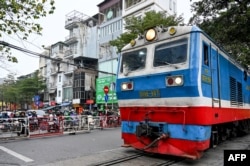 Vehicles wait as a train passes at a railway crossing in Hanoi on Feb. 18, 2025.