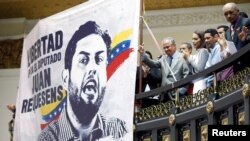 Familiares de presos políticos aplauden junto a una pancarta que representa al legislador detenido Juan Requesens durante la ceremonia de juramento de Juan Guaidó en el congreso de Caracas, Venezuela 5 de enero de 2019.