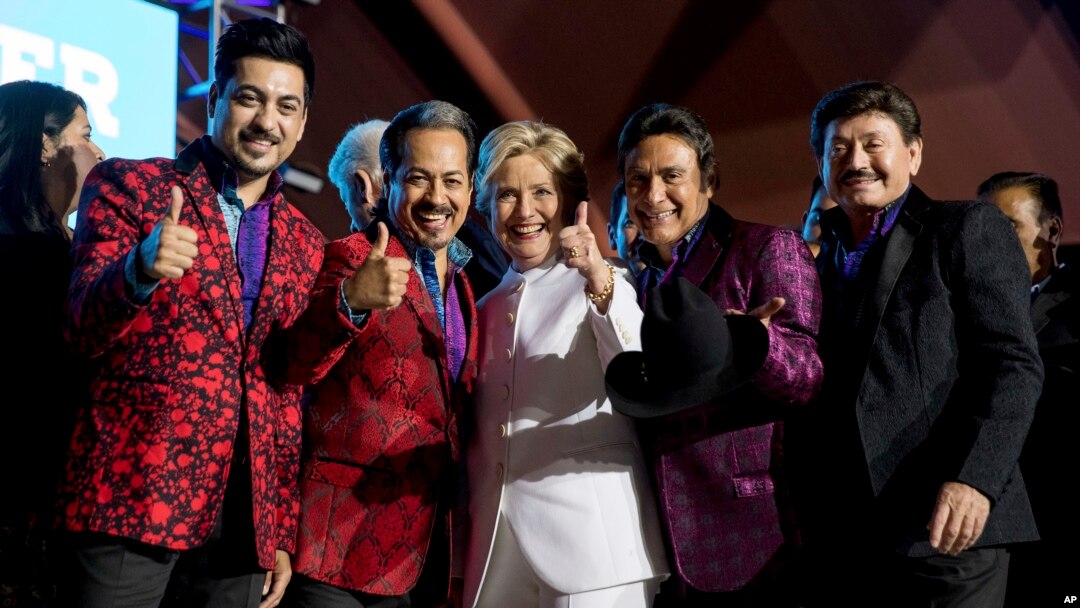 Democratic presidential candidate Hillary Clinton, center, pose with members of the band Los Tigres del Norte at a debate watch party at the Craig Ranch Regional Amphitheater in North Las Vegas, Oct. 19, 2016.