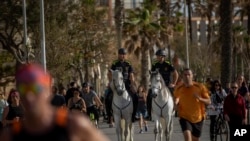 Mounted police patrol on horses as people exercise on a seafront promenade in Barcelona, Spain, Sunday, May 3, 2020.