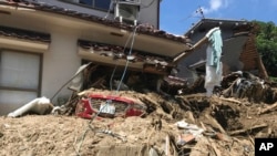 Sebuah mobil tertutup lumpur sementara rumah-rumah di sekitarnya rusak tertimbun tanah longsor akibat hujan lebat di Hiroshima, barat daya Jepang, 10 Juli 2018.