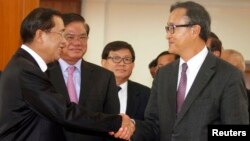 PM Kamboja Hun Sen (kiri) dan pemimpin Partai Penyelamat Nasional Kamboja (CNRP) Sam Rainsy, saling berjabat tangan seusai pertemuan di Phnom Penh (16/9).