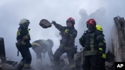 Para petugas penyelamat tampak berusaha membersihkan reruntuhan gedung apartemen yang terkenan serangan roket Rusia di Dnipro, pada 15 Januari 2023. (Foto: AP/Evgeniy Maloletka)