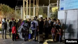 Người tị nạn và di dân đứng trước cổng trại tị nạn Moria đã bị đóng sau vụ cháy, ngày 19 tháng 9 năm 2016. 