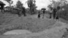 Cambodian villagers walk around bomb crater in a road near embattled Takeo 42 miles southwest of Phnom Penh in Cambodia May 17, 1973. US jets continue to support Khmer government troops against insurgent forces throughout Cambodia despite criticism and threatened congressional action to force an end to the bombing. (AP Photo/Chhor Yuthy)