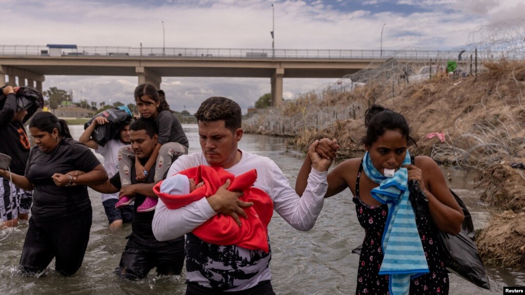 ARCHIVO - Yusniel, un migrante de Cuba, sostiene a su hijo de 10 días, Yireht, y a su esposa, Yanara, mientras buscan un punto de entrada más allá de una cerca de alambre a lo largo de la orilla del río Grande en Eagle Pass, Texas, EEUU, el 6 de octubre de 2023.