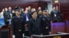 Mantan ketua Asosiasi Sepak Bolah China, Chen Xuyuan (tengah), beridir saat hadir dalam persidangan kasus yang menjeratnya di Pengadilan Huangshi, Hubei, pada 26 Maret 2024. (Foto: Handout/Huangshi Intermediate People's Court/AFP)