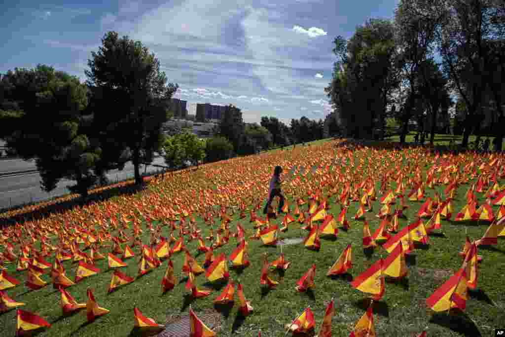 A woman walks among the flags placed in memory of coronavirus (COVID-19) victims in Madrid, Spain.