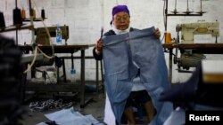 Pegawai pabrik garmen di Jakarta sedang mengukur kain untuk celana. 