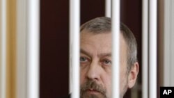 Former presidential candidate Andrei Sannikov sits in a cage during a court hearing in Minsk, April 27, 2011