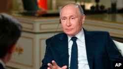 Le président russe Vladimir Poutine s'entretient avec le journaliste de NBC News Keir Simmons, dos à une caméra, dans une interview diffusée le lundi 14 juin 2021.