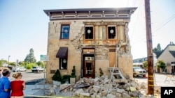 Pedestrians stop to examine a crumbling building in Napa, California, following an earthquake, Aug. 24, 2014. (AP Photo/Noah Berger)