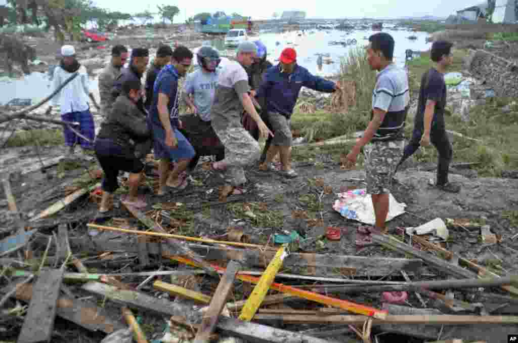 Residents carry a body bag containing the body of a tsunami victim in Palu, Central Sulawesi, Indonesia, Sept. 29, 2018.