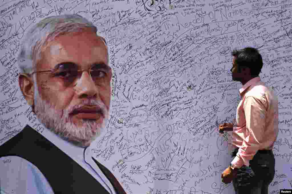 A man prepares to sign a board with a picture of Hindu nationalist Narendra Modi, the presumptive prime minister of India and leader of the opposition Bharatiya Janata Party (BJP), at the BJP headquarters, in New Delhi, May 16, 2014.