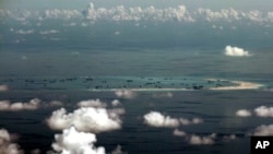 FILE - In this Monday, May 11, 2015, file photo, This photo taken through a glass window of a military plane shows China's alleged on-going reclamation of the Spratly Islands in the South China Sea. 