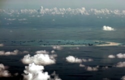 FILE - This aerial photo taken through a glass window of a military plane shows part of the Spratly Islands in the South China Sea, May 11, 2015.