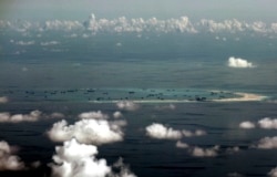 FILE - This aerial photo taken through a glass window of a military plane shows China's alleged on-going reclamation of Mischief Reef in the Spratly Islands in the South China Sea, May 11, 2015.