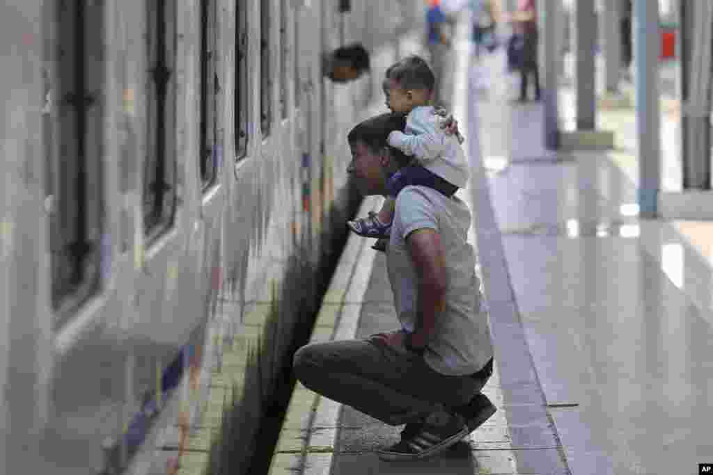 Seorang pria menggendong anaknya melihat ke jendela kereta api di Stasiun Pasar Senen, Jakarta, 31 Mei 2019. Warga Jakarta mulai mudik ke daerah masing-masing untuk merayakan Idul Fitri bersama keluarga. (Foto: AP)