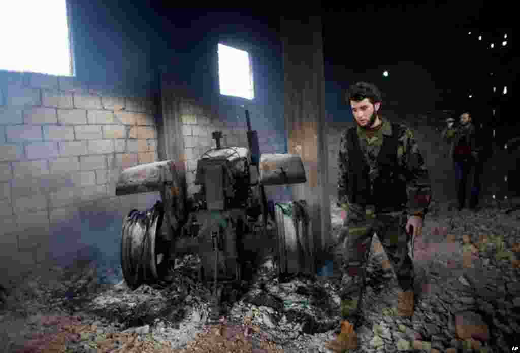 A Free Syrian Army soldier next to a burned tractor in Sarmin, north Syria, February 28, 2012 (AP)