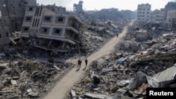 Palestinians walk past destroyed houses, amid the ongoing conflict between Israel and Hamas, in Jabalia refugee camp, in the northern Gaza Strip, Feb. 22, 2024. 