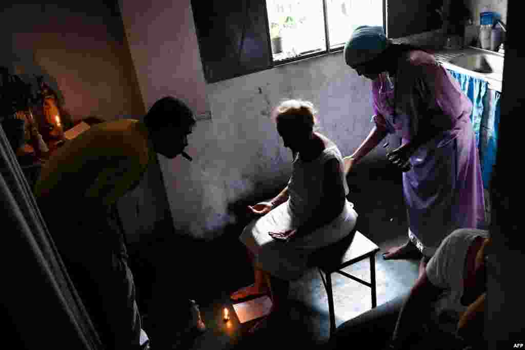 Esperanza Castillo (C), 74, is treated at the clinic of spiritual healer &quot;Guayanese Brother&quot; in Petare neighborhood, Caracas. Venezuelans turn to alternative treatments and the use of herbs due to the lack of and high cost of medicine.