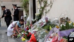 A woman leaves flowers in front of the Carabinieri station where Mario Cerciello Rega was based, in Rome, Saturday, July 27, 2019. 