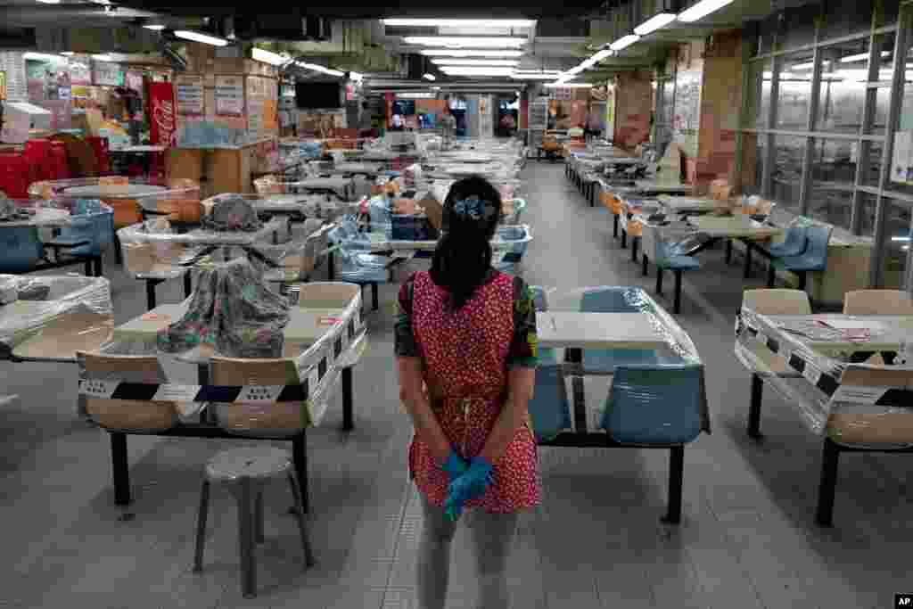 A restaurant employee looks at empty tables at a Chinese food court in Hong Kong. Hong Kong has completely banned dining-in at restaurants as the region battles its worst coronavirus outbreak to date
