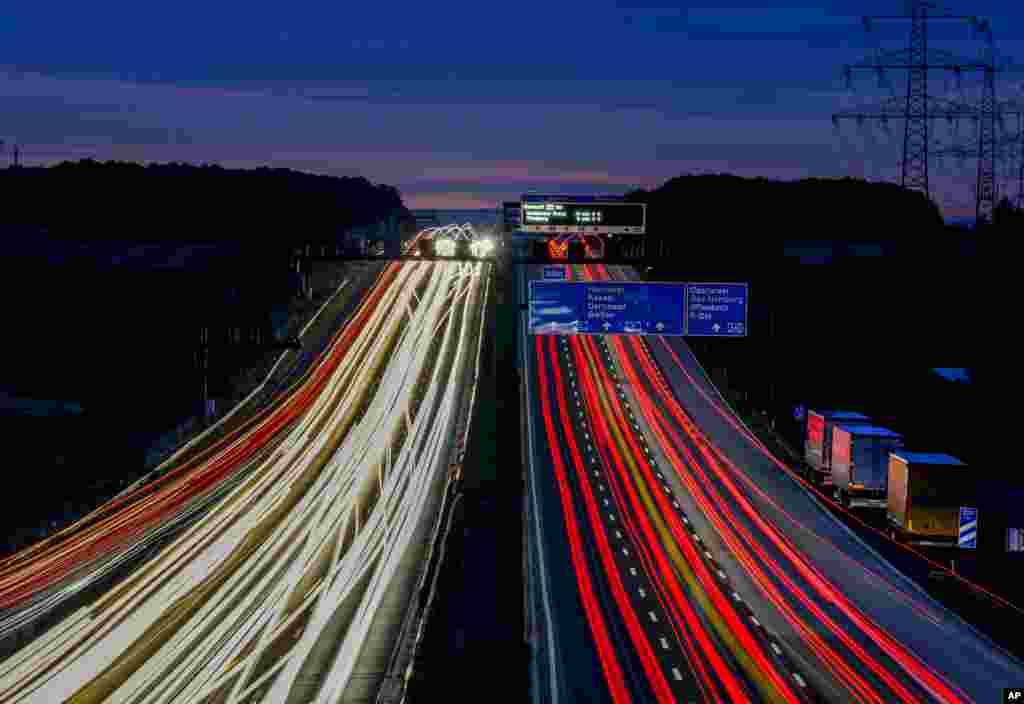 A long camera exposure shows vehicles driving along a highway in Frankfurt, Germany, before sunrise.