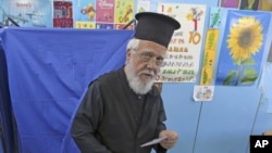 A Greek Orthodox priest holds his ballot paper as he exits a voting booth at an Athens primary school used as a polling station, during Greece's general election, May 6, 2012. 