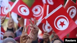 Des Tunisiens agitent des drapeaux lors d'une manifestation à Tunis le 14 février 2018 