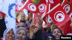 Warga mengibarkan bendera nasional saat berdemo pada peringatan 7 tahun penggulingan Presiden Zine El-Abidine Ben Ali, di Tunis, 14 Januari 2018.