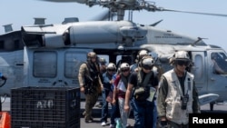 Sailors from the Dwight D. Eisenhower Carrier Strike Group assist mariners rescued from the Liberian-flagged, Greek-owned bulk carrier M/V Tutor that was attacked by Houthis, in the Red Sea, June 15, 2024. (U.S. Naval Forces Central Command/U.S. 5th Fleet/Handout via REUTERS) 