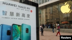 在中国上海的Apple商店外面，顾客排队购买新的iPhone XR手机，附近有华为Mate 20系列产品的广告。（2018年10月26日）