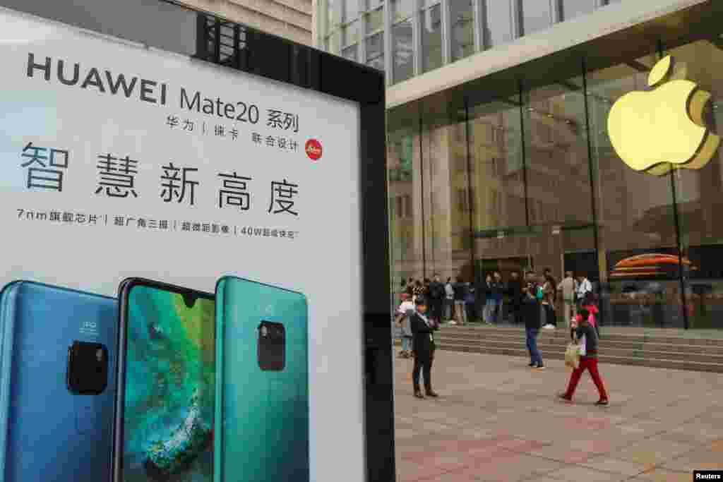 2018年10月26日在中国上海的Apple商店外面，顾客排队购买新的iPhone XR手机，附近有华为Mate 20系列产品的广告。