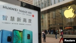 中国上海的苹果商店外面，顾客排队购买新的iPhone XR手机，附近有华为Mate 20系列产品的广告。（2018年10月26日）