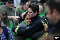 FILE - A woman hugs a fire-fighter as members of the public take part in a silent march as part of commemorations on the first anniversary of the Grenfell fire in west London, June 14, 2018.