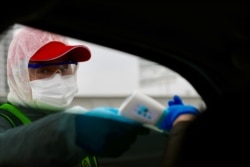 A worker measures the body temperature of a passenger inside a vehicle following an outbreak of the novel coronavirus in Wuhan, Hubei province, China, Feb. 7, 2020.