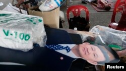 Boneka karton mantan perdana menteri Thailand Thaksin Shinawatra dekat jenazah seorang pria yang tewas dalam demonstrasi anti-pemerintah di Bangkok (1/12). 