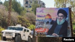 Një autoblindë e paqeruajtësve të OKB-së duke kaluar pranë një banderole të ngritur në vitin 2022 ku shfaqet ish-udhëheqësi i Hezbollahut, Sayyed Hassan Nasrallah