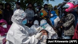 Para pengendara motor sedang menjalani tes usap (swab) COVID-19 di pos pemeriksaan di Surabaya, Minggu, 6 Juni 2021. (Foto: Juni Kriswanto/AFP)