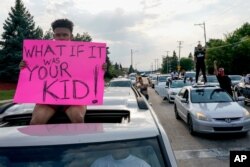 A protester sits on a car as they stop traffic, Aug. 24, 2020, in Kenosha, Wis. Wisconsin Gov. Tony Evers has summoned the National Guard to head off another round of violent protests.