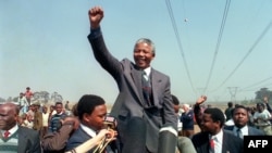 FILE - Anti-apartheid leader Nelson Mandela raises his fist while addressing a crowd of residents from the Phola Park squatter camp during his tour of townships, in Tokoza, Sept. 5, 1990.