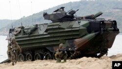 U.S. Marines jump off an amphibious assault vehicle after hitting the ground at a joint military exercise on Hat Yao beach in Chonburi province eastern, Thailand, February 10, 2012.