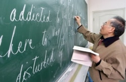 FILE - A Chinese teacher writes English words on a blackboard at a class in Shanghai, April 26, 2002.