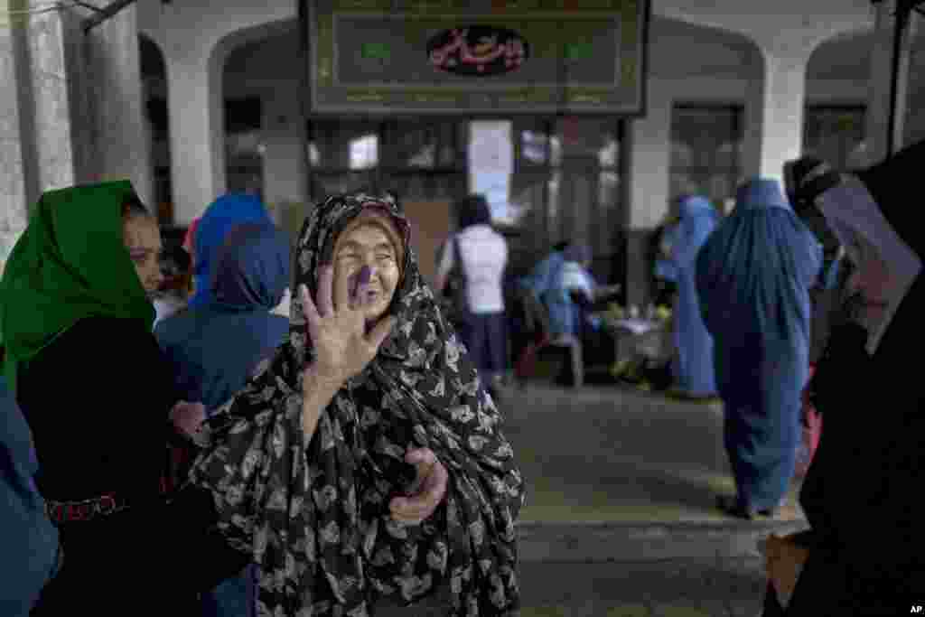 An elderly woman shows another woman her inked finger after casting her ballot at a polling station in Kabul.