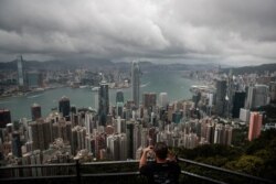 FILE - A visitor sets up his camera in the Victoria Peak area to photograph Hong Kong's skyline, Sept. 1, 2019.