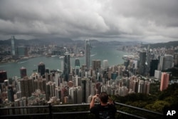 FILE - A visitor sets up his camera in the Victoria Peak area to photograph Hong Kong's skyline, Sept. 1, 2019.