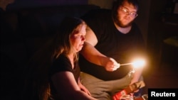 FILE - Christina Beverly and John Shearon light candles in their home after winter weather caused electricity blackouts and 'boil water notices in Fort Worth, Texas, Feb. 20, 2021. 