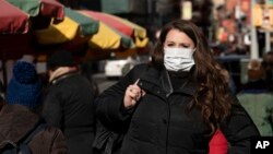 A woman, who declined to give her name, wears a mask, Thursday, Jan. 30, 2020 in New York. She works for a pharmaceutical company and said she wears the mask out of concern for the coronavirus. 